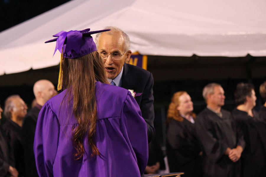 The Apple Leaf file photo. School Board member Dr. Walter Newman congratulates a Wenatchee High School senior with her diploma at the 2014 commencement.  