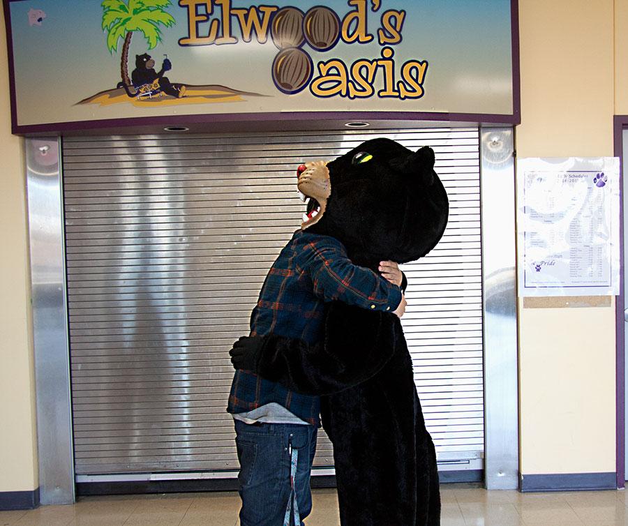 The Wenatchee High School mascot, Elwood the panther, hugs a WHS student during a photoshoot outside the store named after him. 