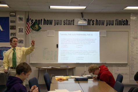 With his words of wisdom on the wall behind him, DECA Adviser Matt Pakinas teaches a marketing class in room 551.