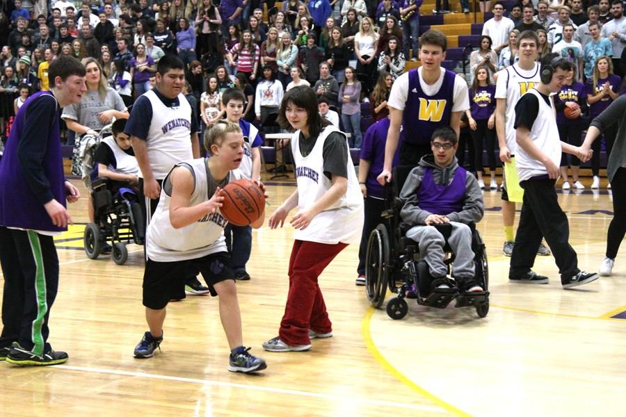 Pioneer Middle School student Daniel George takes the ball down the court for the Pack the Gym game. Wenatchee High Schools Star Ward assists him.