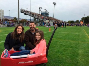 Makenna Schwab, and her parents Melissa and Shawn, pose at the end of the football field after receiving donations to Makenna's Make A Difference Day project.