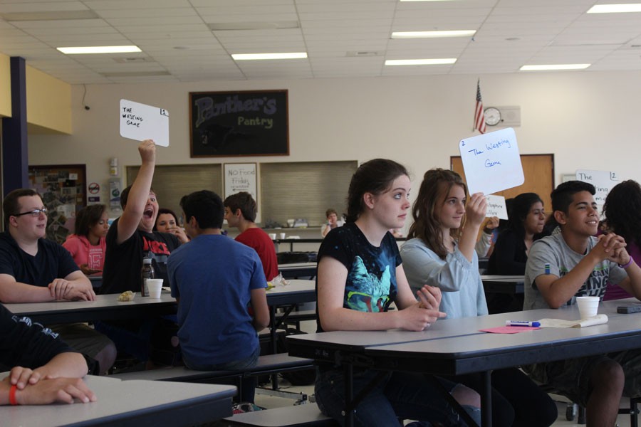 Students raise their answer printed on white boards. The students have read several novels since February in preparation for the competition.