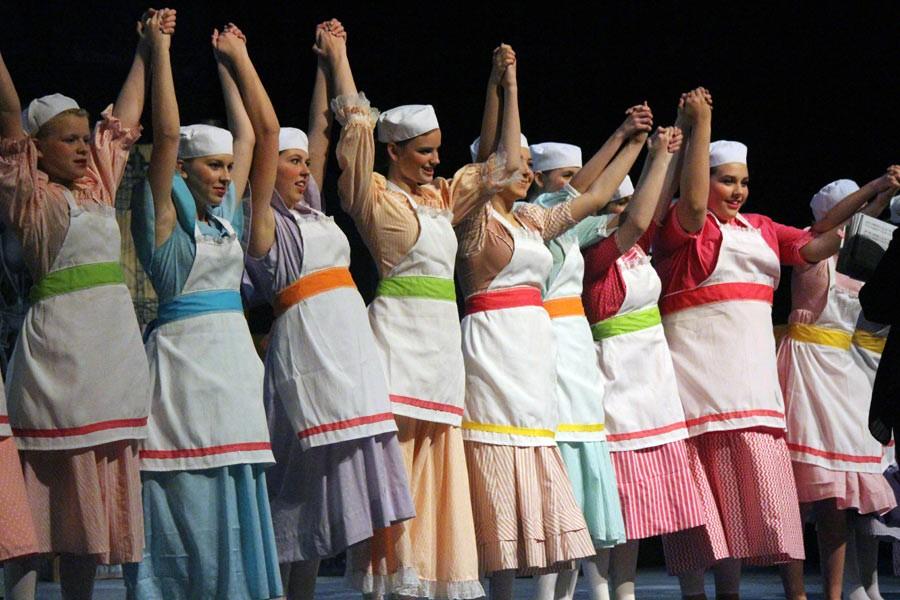 Students lock hands in unison to take their bows in colorful costume.
