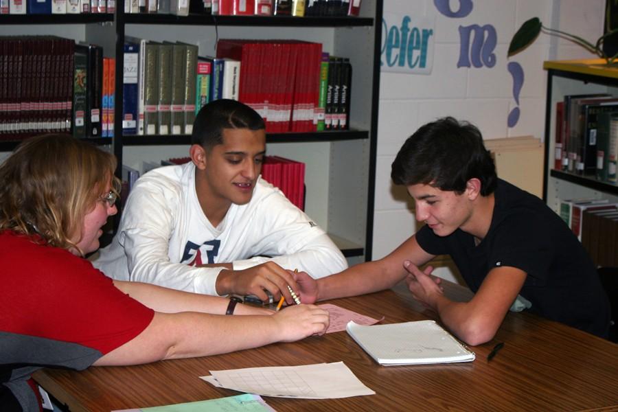 Homework Center supervisor Paula Fendley helps students Oscar Mendoza and Tanner Williams with math.